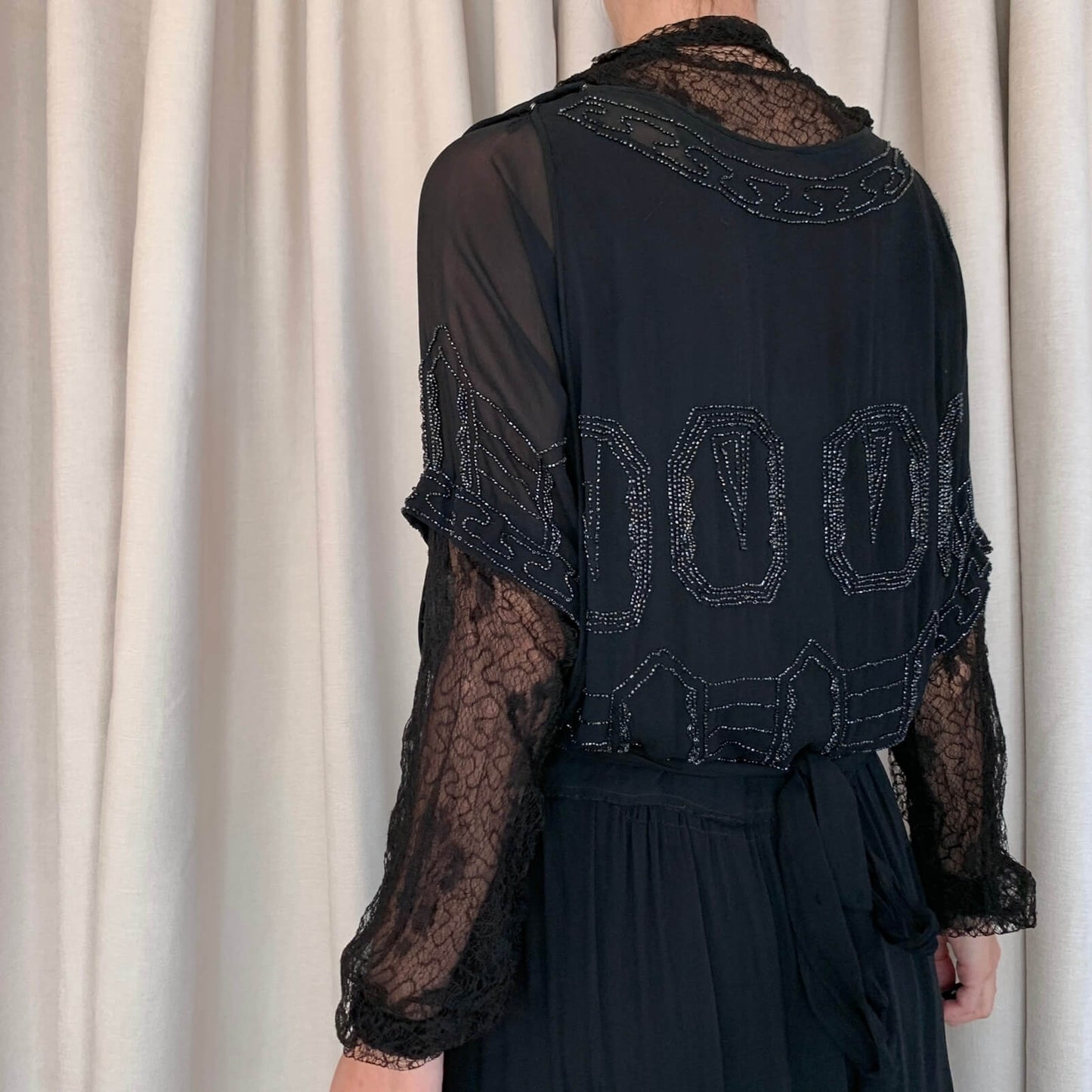 back view of a black vintage beaded dress with lace sleeves
