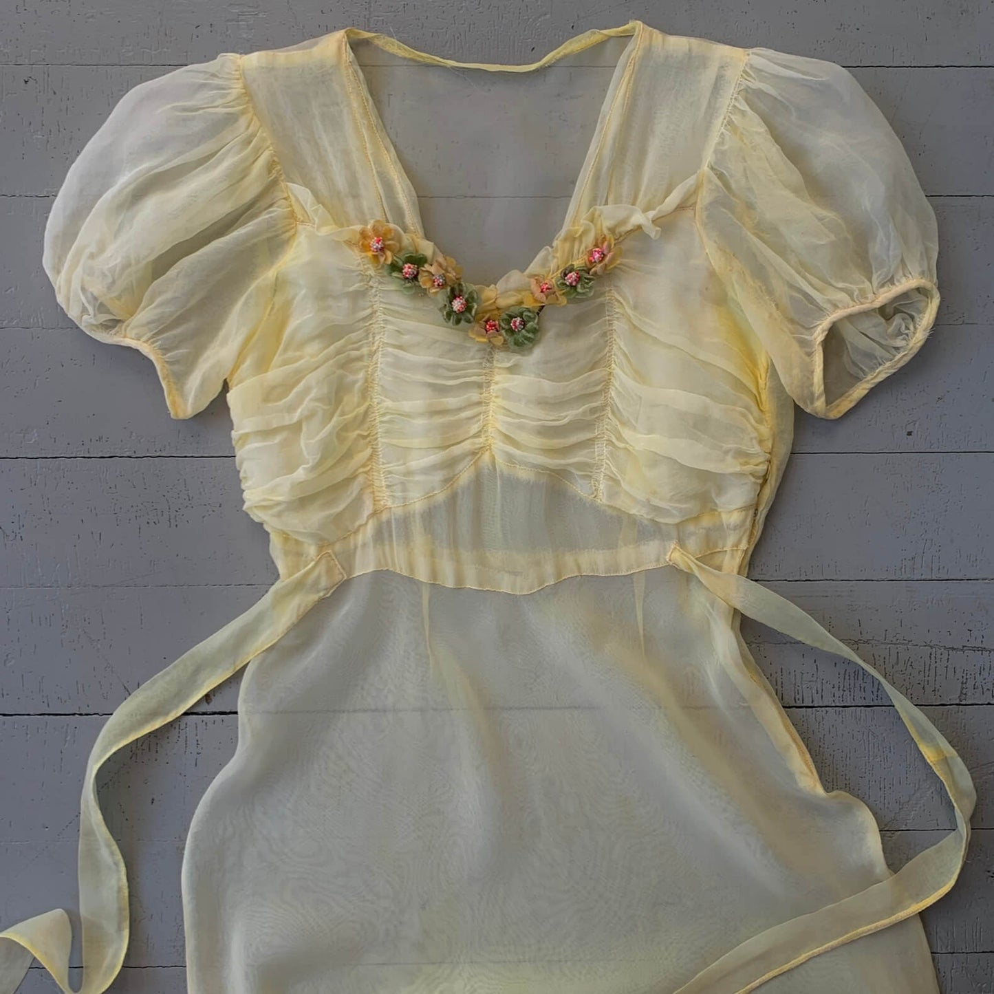yellow 1930s sheer gown with floral applique laid flat