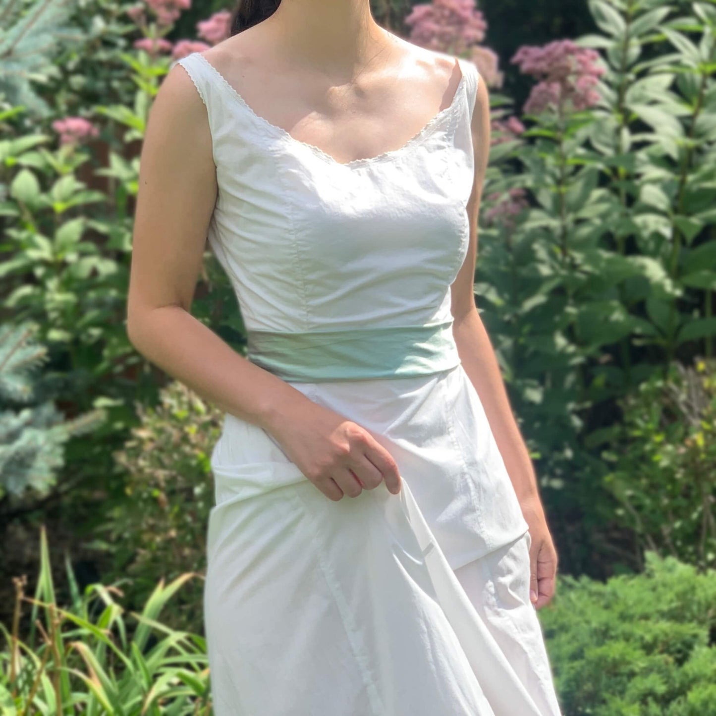 girl standing in a yard wearing an antique wedding dress