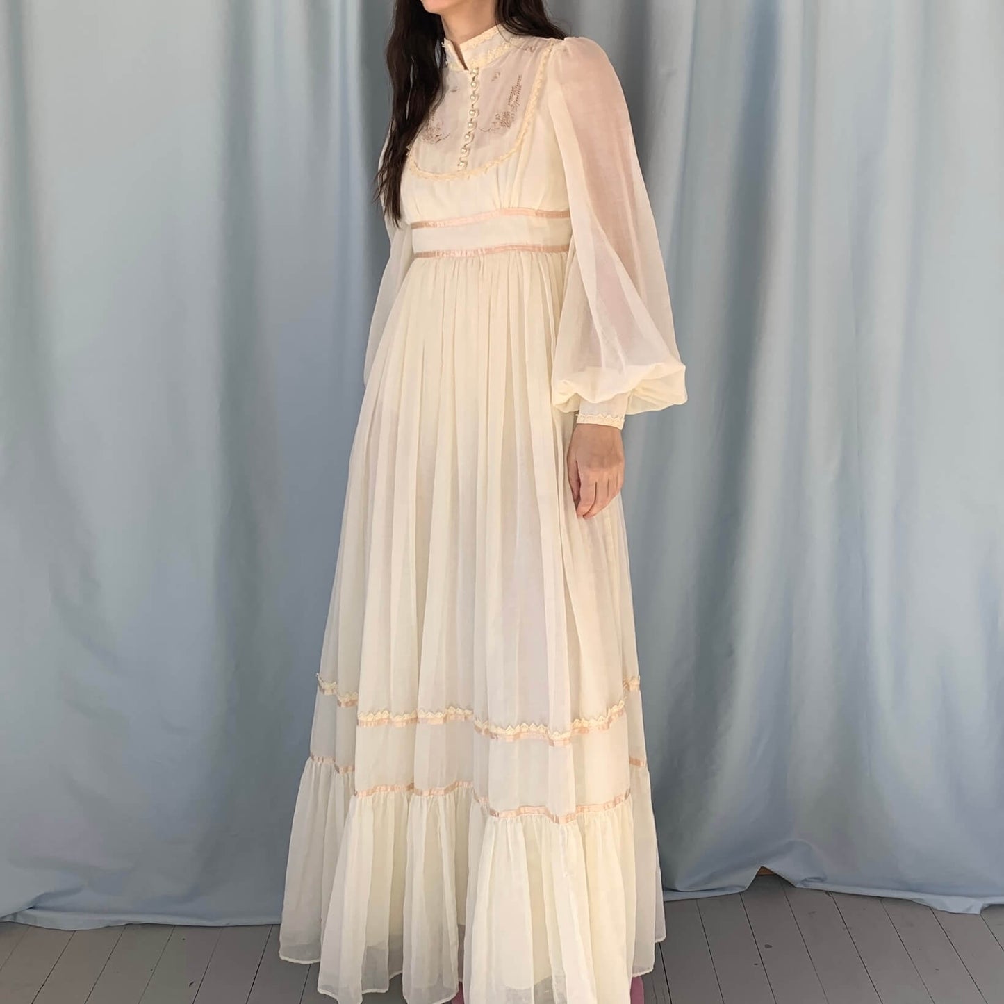 70s Gunne Sax Wedding Dress in ivory cotton in front of a blue backdrop