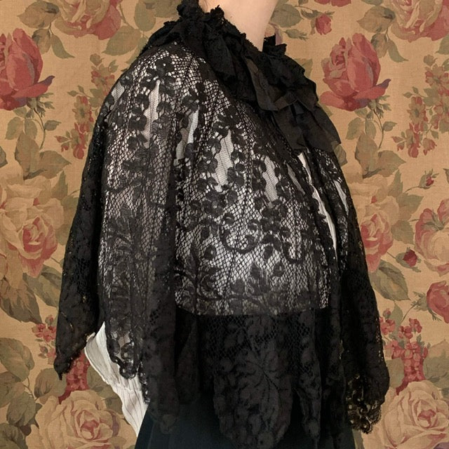 Side view of the lace capelet against a brown backdrop