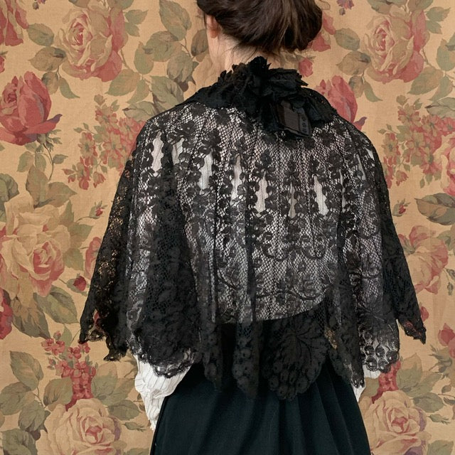 woman in a black lace short cape on top of white shirt and black skirt