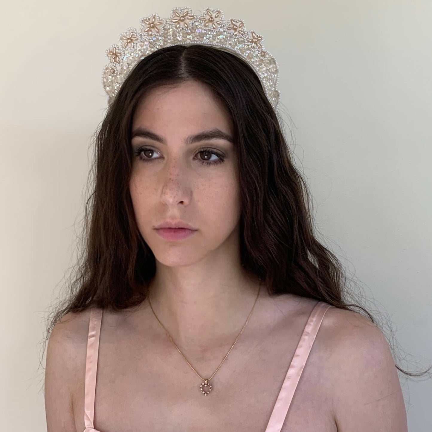 1930s vintage bridal crown with pearlescent flowers on model in front of a white background