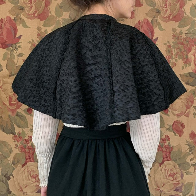 back view of the vintage capelet made of textured black fabric